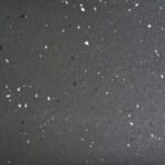 AU20-2056CX anti-slip PVC flooring texture for bus and coach interiors, a charcoal-gray base with sparse black and white chips
